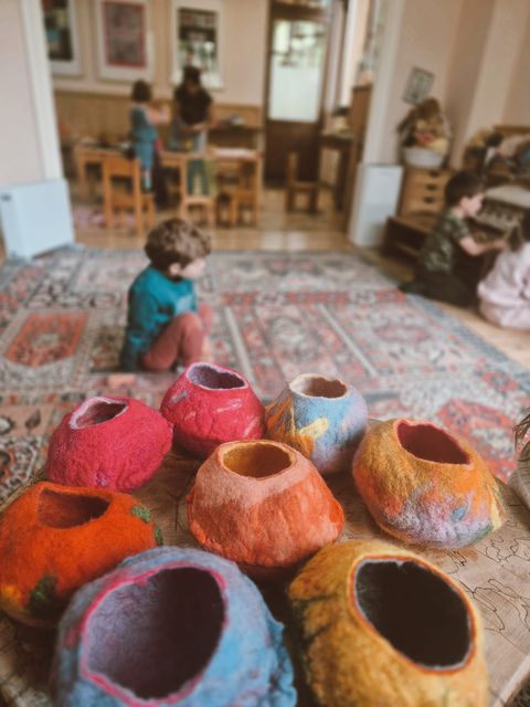 A row of colourful felted bowls on a wooden table